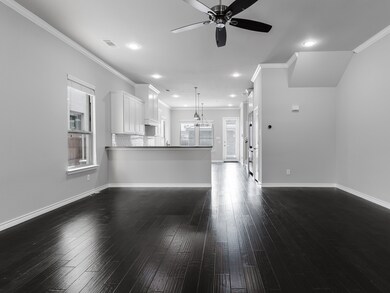 Unfurnished living room featuring crown molding, a ceiling fan, dark wood-type flooring, and recessed lighting