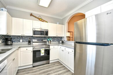 Kitchen with appliances with stainless steel finishes, crown molding, light countertops, a textured ceiling, and white cabinets