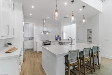 Kitchen with a sink, wall chimney range hood, back