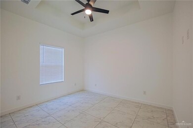 Empty room with light marble finish flooring, a ceiling fan, and a tray ceiling