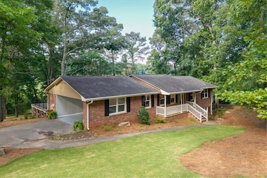 Ranch house featuring covered porch, driveway, brick siding, a front yard, and an attached carport.