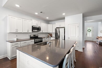 Kitchen featuring appliances with stainless steel finishes, backsplash, dark wood-type flooring, white cabinets, and recessed lighting