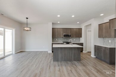 Kitchen featuring tasteful backsplash, modern cabinets, hanging light fixtures, an island with sink, and light wood finished floors
