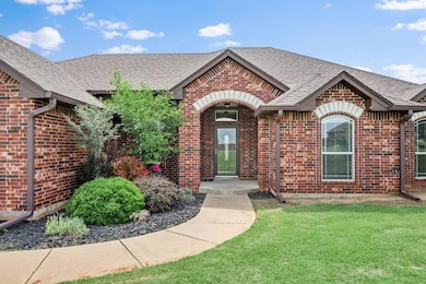 View of front facade featuring brick siding, a shingled roof, and a front lawn