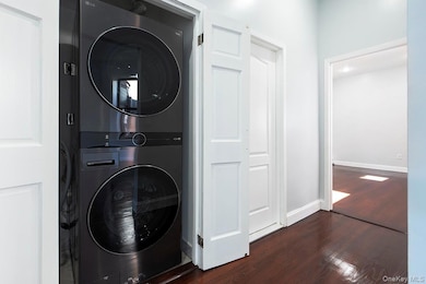 Laundry area featuring estacked washer and dryer and dark wood-type flooring