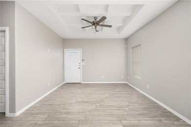 Empty room with coffered ceiling, a ceiling fan, light wood finished floors, and beam ceiling