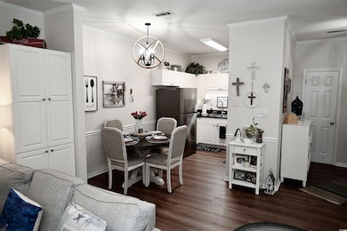 Dining room featuring dark wood-style floors, a chandelier, and ornamental molding