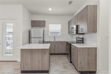 Kitchen with stainless steel appliances, light wood-style floors, light countertops, a kitchen island, and tasteful backsplash
