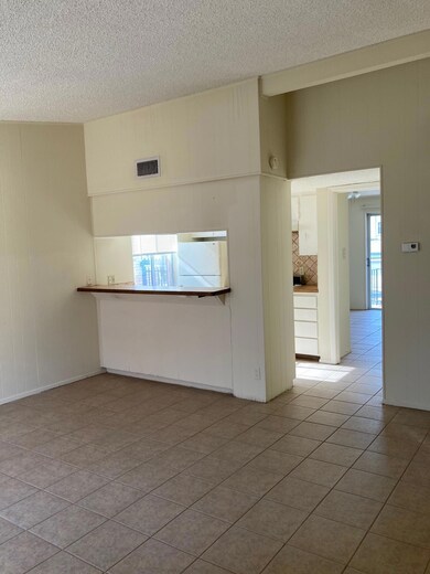Tiled empty room featuring a textured ceiling