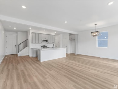 Unfurnished living room with recessed lighting, light wood-type flooring, stairs, and a chandelier