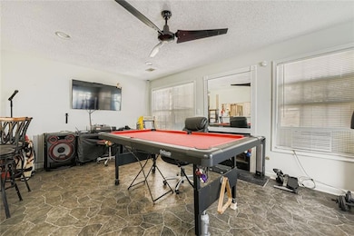 Rec room featuring dark stone finish flooring, a textured ceiling, pool table, and a ceiling fan