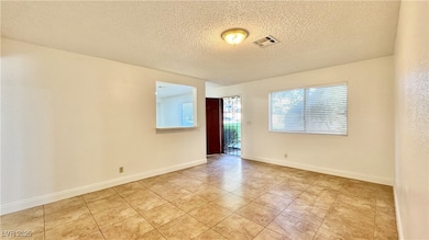 Empty room featuring a textured ceiling, light til