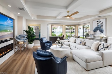 Living area featuring wood finished floors, a fireplace, ceiling fan, beam ceiling, and coffered ceiling