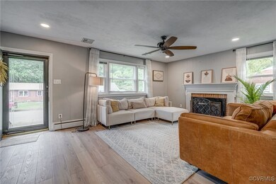 Living room with light wood-type flooring, a brick fireplace, plenty of natural light, and ceiling fan