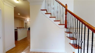 Stairs with baseboards, recessed lighting, wood finished floors, and ornamental molding