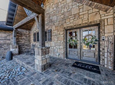 Property entrance with stone siding and a patio area
