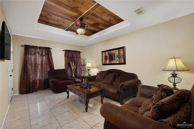 Living room with ceiling fan, baseboards, wooden ceiling, a tray ceiling, and visible vents