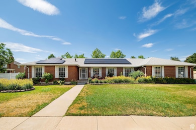 Ranch-style house featuring brick siding and fully-owned roof mounted solar panels