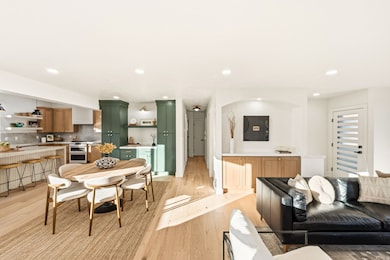 Living room and dining area with light wood flooring and recessed lighting