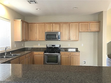 Kitchen with appliances with stainless steel finishes, recessed lighting, and dark stone countertops