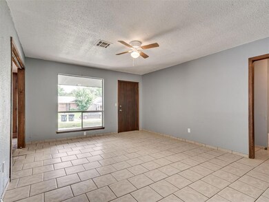 Tiled spare room featuring ceiling fan and a textured ceiling