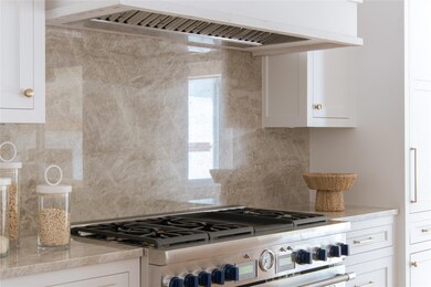 Kitchen with white cabinets, backsplash, and range