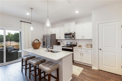 Kitchen with appliances with stainless steel finishes, a kitchen bar, white cabinets, backsplash, and recessed lighting