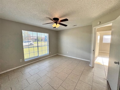 Tiled spare room with a textured ceiling, ceiling fan, and plenty of natural light
