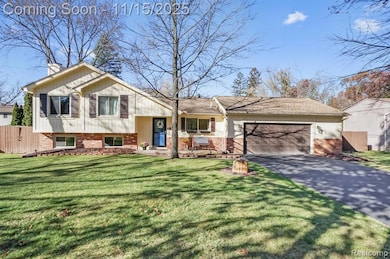 Tri-level home featuring brick siding, driveway, a chimney, and an attached garage