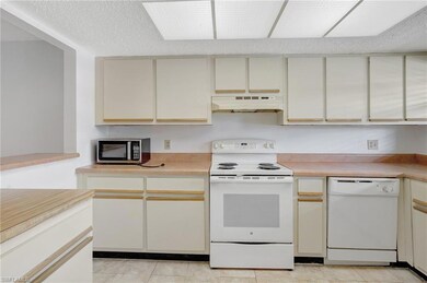 Kitchen featuring white appliances, light countert