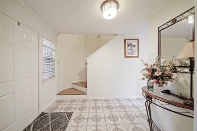 Bright and welcoming entryway with tile flooring and a staircase leading up.