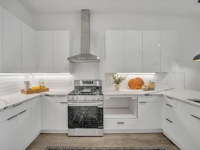 Kitchen with white cabinetry, light stone countert