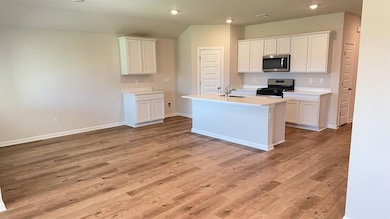 Kitchen with white cabinets, stainless steel appliances, light countertops, light wood-style floors, and recessed lighting