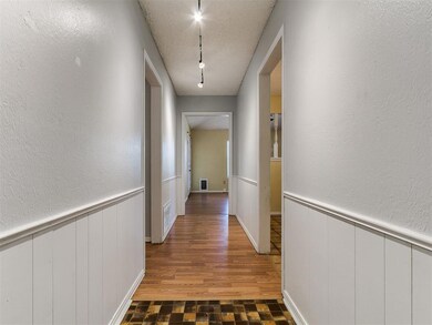 Hallway featuring visible vents, wainscoting, rail
