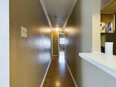 Corridor with crown molding, wood finished floors