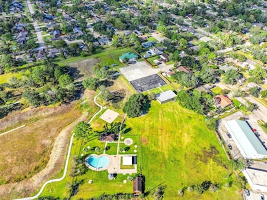 This aerial photo is of the neighborhood park, pool and trails just waiting for you! There's a large open field, a paved area, and a swimming pool with surrounding amenities, ideal for recreation. The neighborhood features tree-lined streets and is well-spaced, providing a serene and inviting environment.