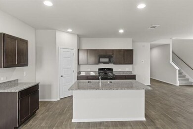 Kitchen featuring black microwave, stove, dark br