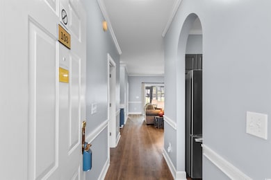 Corridor featuring arched walkways, ornamental molding, and dark wood-style flooring