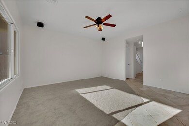 Carpeted empty room with ceiling fan and tile patt
