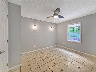 Empty room featuring a textured ceiling, a ceiling fan, and light tile patterned floors
