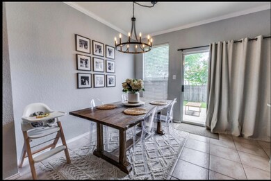 Dining space featuring a textured wall, ornamental molding, light tile patterned flooring, and a chandelier