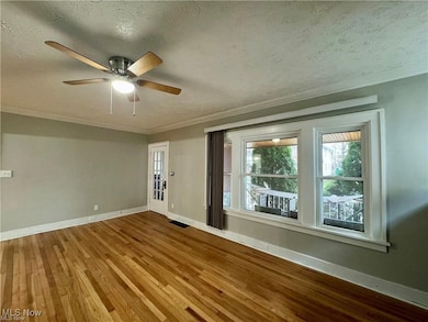 Empty room with baseboards, visible vents, wood finished floors, and crown molding