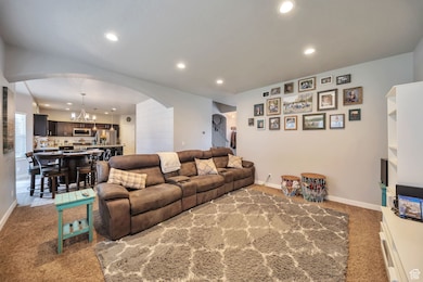 Living room featuring arched walkways, recessed lighting, a chandelier, and light colored carpet