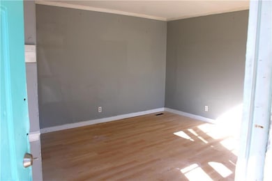 Unfurnished room featuring wood finished floors, baseboards, and ornamental molding