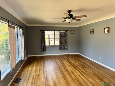 Spare room with wood finished floors, ceiling fan, and a textured ceiling