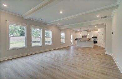 Unfurnished living room featuring beamed ceiling, light wood-type flooring, baseboards, crown molding, and recessed lighting