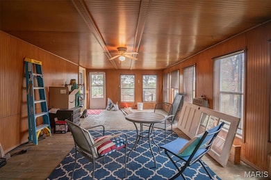 Living area with wood walls, a ceiling fan, and wood finished floors