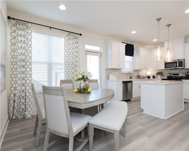 Kitchen featuring stainless steel appliances, white cabinetry, light wood-type flooring, tasteful backsplash, and recessed lighting