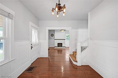 Foyer with an inviting chandelier, a brick fireplace, and dark wood-type flooring