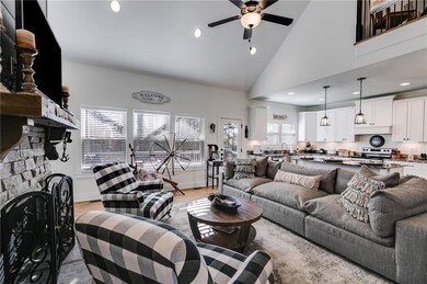 Living room with a stone fireplace, a ceiling fan,